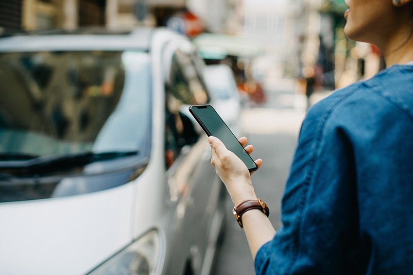 Femme tenant un téléphone et regardant une voiture